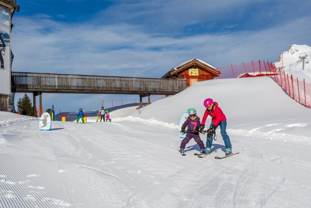 A female ski instructor from the Davos Skischool skiing with a small child.
